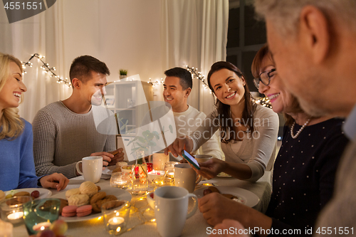 Image of happy family with smartphone at tea party at home