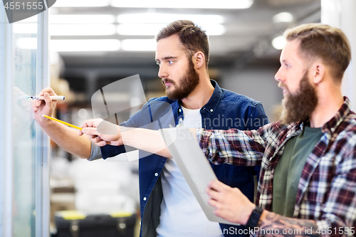 Image of men writing to clipboard and whiteboard at office