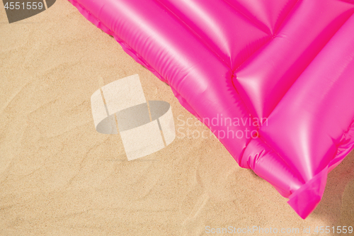 Image of pink swimming mattress on beach