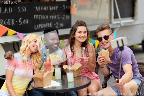 Image of happy young friends taking selfie at food truck