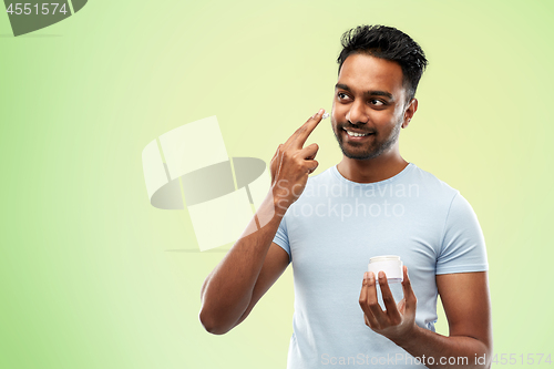 Image of happy indian man applying cream to face