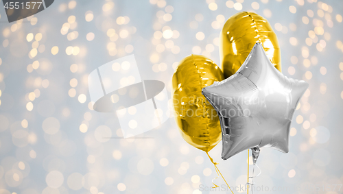 Image of three gold and silver helium balloons on white