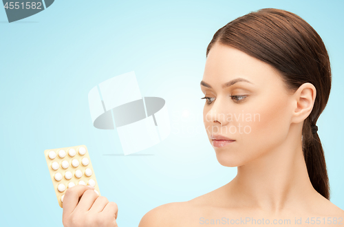 Image of young woman with pills over blue background