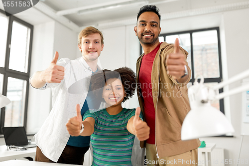 Image of happy creative team showing thumbs up at office