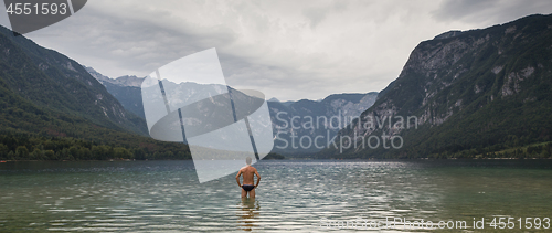 Image of Man going to swim in freezing cold lake Bohinj, Alps mountains, Slovenia, on tranquil overcast morning