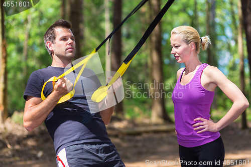 Image of Young active people training with fitness straps outdoors.