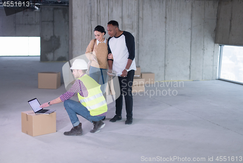 Image of engineer showing house design plans to a young multiethnic coupl