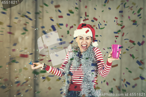 Image of business woman wearing a red hat and blowing party whistle