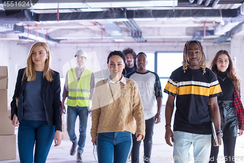 Image of young multiethnic business people walking through unfinished sta