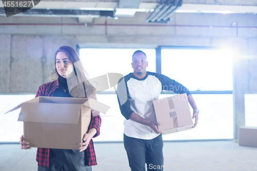 Image of multiethnic business team carrying cardboard boxes