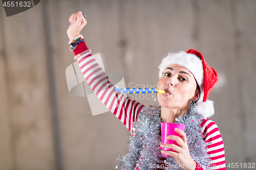 Image of young business woman wearing a red hat and blowing party whistle