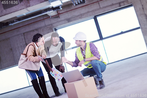 Image of engineer showing house design plans to a young multiethnic coupl