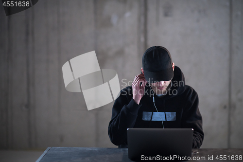 Image of talented hacker using laptop computer while working in dark offi