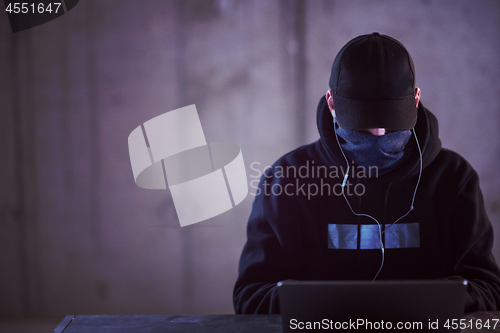 Image of talented hacker using laptop computer while working in dark offi