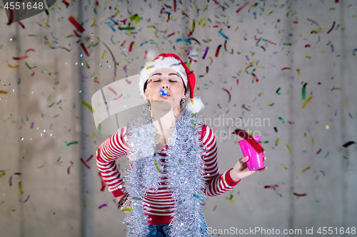 Image of business woman wearing a red hat and blowing party whistle