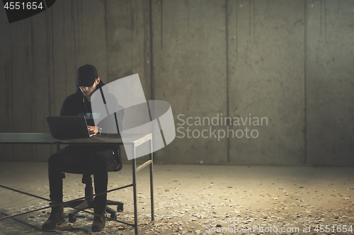 Image of talented hacker using laptop computer while working in dark offi