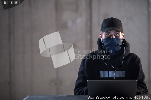 Image of talented hacker using laptop computer while working in dark offi