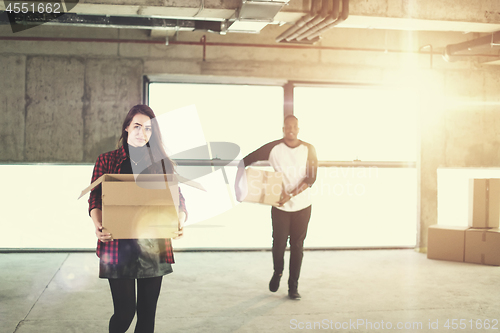 Image of multiethnic business team carrying cardboard boxes