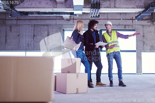 Image of architect showing house design plans to a young couple