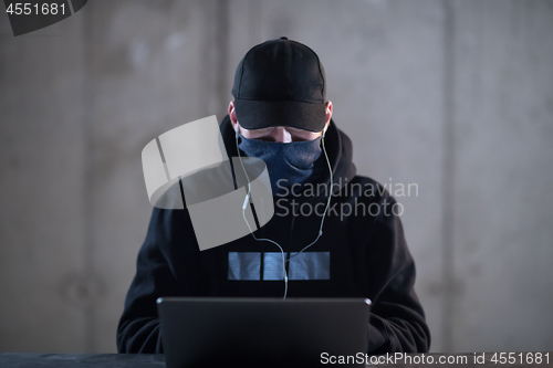 Image of talented hacker using laptop computer while working in dark offi