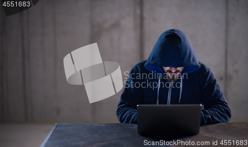 Image of talented hacker using laptop computer while working in dark offi