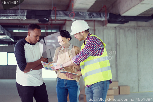 Image of architect showing house design plans to a young multiethnic coup