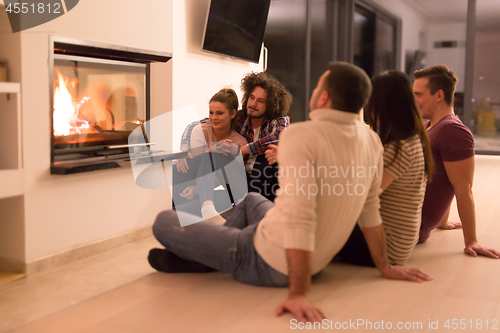 Image of multiethnic couples sitting in front of fireplace