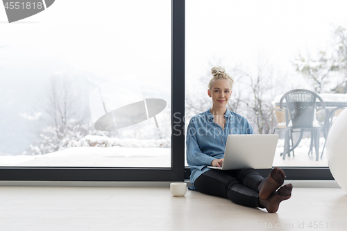 Image of woman drinking coffee and using laptop at home