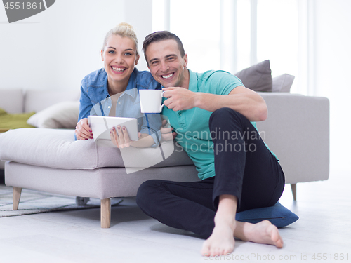 Image of couple relaxing at  home with tablet computers