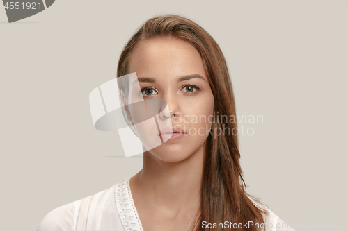 Image of The serious business woman standing and looking at camera against gray background.