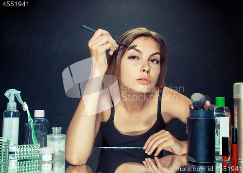 Image of Beauty woman applying makeup. Beautiful girl looking in the mirror and applying cosmetic with a big brush.