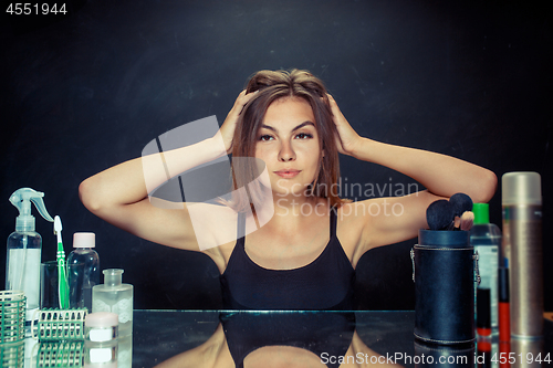 Image of Beauty woman after applying makeup. Beautiful girl looking in the mirror and applying cosmetic with a brush.