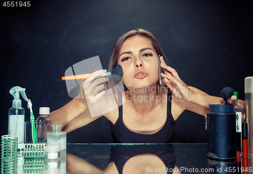 Image of Beauty woman applying makeup. Beautiful girl looking in the mirror and applying cosmetic with a big brush.