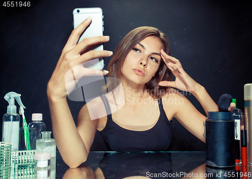 Image of Beauty woman with makeup. Beautiful girl looking at the mobile phone and making selfie photo