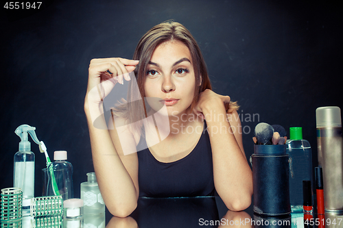 Image of Beauty woman applying makeup. Beautiful girl looking in the mirror and applying cosmetic with a big brush.