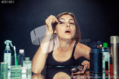 Image of Beauty woman applying makeup. Beautiful girl looking in the mirror and applying cosmetic with a brush.