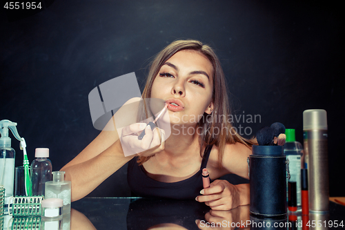 Image of Beauty woman applying makeup. Beautiful girl looking in the mirror and applying cosmetic with a brush.