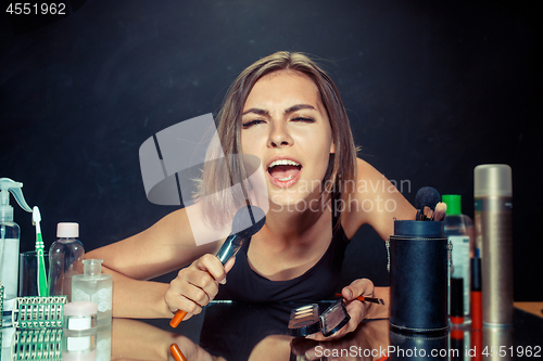 Image of Beauty woman applying makeup. Beautiful girl looking in the mirror and applying cosmetic with a big brush.