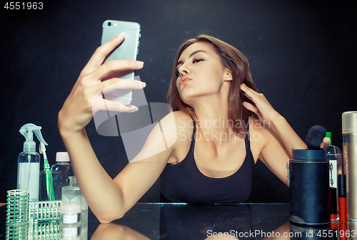 Image of Beauty woman with makeup. Beautiful girl looking at the mobile phone and making selfie photo