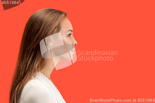 Image of The serious business woman standing against red background.