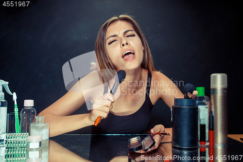 Image of Beauty woman applying makeup. Beautiful girl looking in the mirror and applying cosmetic with a big brush.