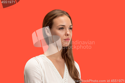 Image of The serious business woman standing and looking at camera against red background.