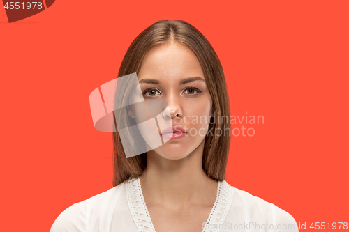 Image of The serious business woman standing and looking at camera against red background.