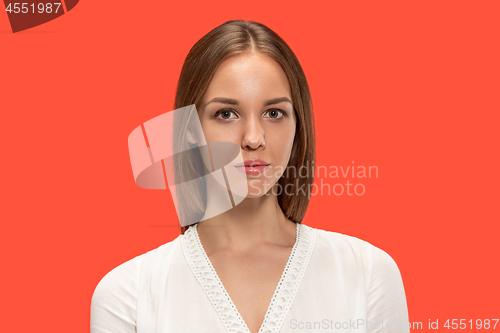 Image of The serious business woman standing and looking at camera against red background.