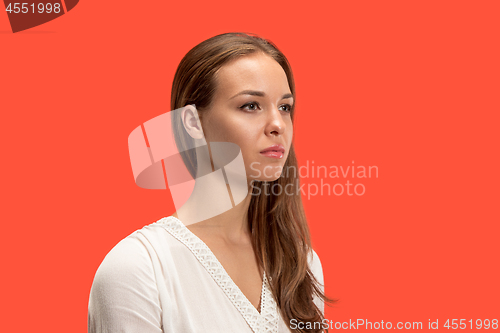 Image of The serious business woman standing and looking at camera against red background.