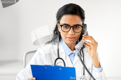 Image of doctor with clipboard calling on phone at hospital