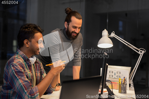 Image of creative team with computer working late at office