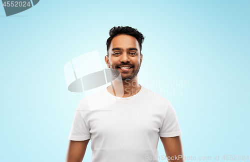 Image of smiling young indian man over blue background