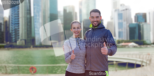 Image of happy couple showing thumbs up over singapore city
