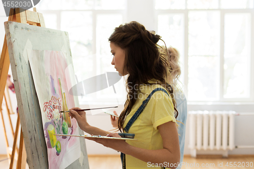 Image of woman with easel painting at art school studio